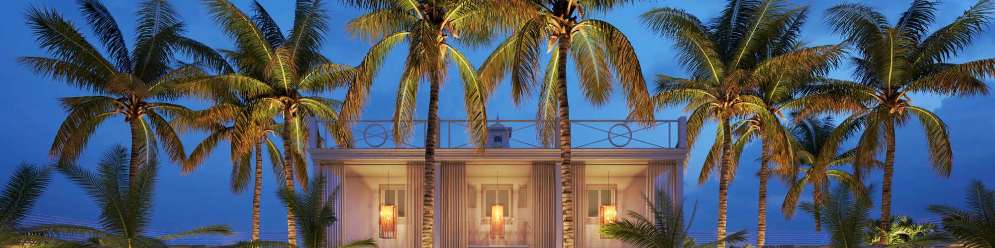 A luxurious building surrounded by palm trees is illuminated at night, with a patterned pathway in the foreground.