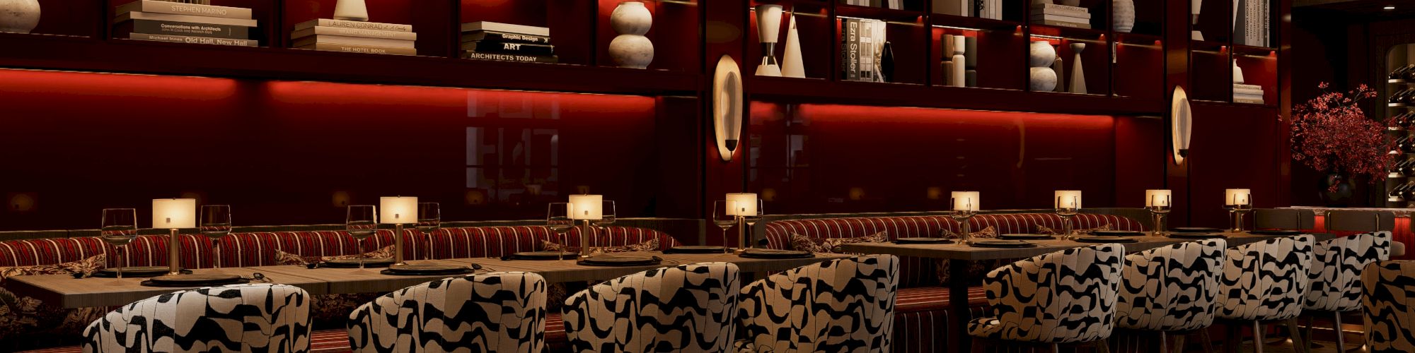 The image shows a dimly lit bar with elegant chandeliers, plush patterned seating, and shelves displaying decorative items and books.